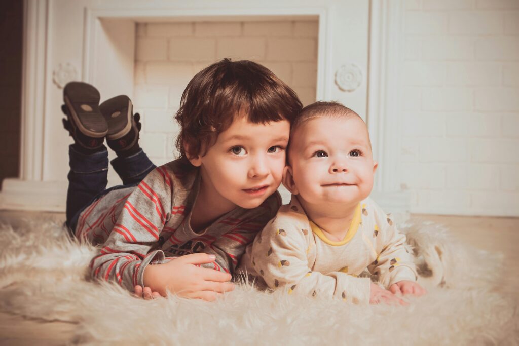 Two young siblings lying on a fluffy rug indoors, exemplifying warmth and family bonding.