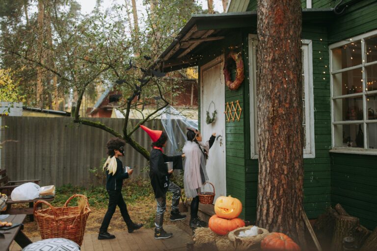 Group of kids in Halloween costumes trick or treating at a house.